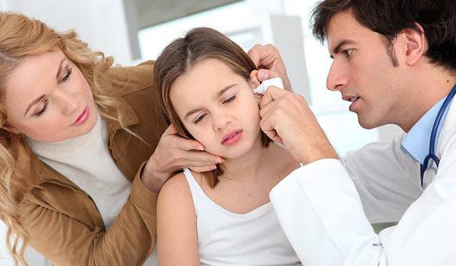 Доктор закапывает лекарство ребенку в ухо